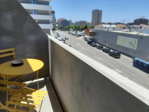 a yellow table and chair on a balcony with a highway at White Design Apartment in Aveiro