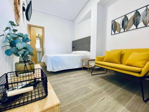 sala de estar con sofá amarillo y cama en Apartamentos Turísticos Santo Rostro, en Chipiona