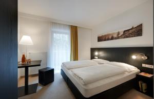 a bedroom with a large white bed and a desk at Hotel Tirolerhof in Rodengo