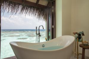 La salle de bains est pourvue d'une baignoire et offre une vue sur l'océan. dans l'établissement Drift Thelu Veliga Retreat, à Dhangethi