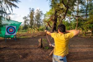 a man is holding a bow and a arrow at Lotus A Eco Beach Resort Dapoli Murud in Dapoli