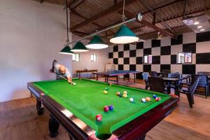 a man standing over a pool table in a room at Lotus an Eco Beach Resort Dapoli Murud in Dapoli