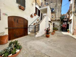 un vicolo con una porta in legno e alcune piante in vaso di Casa Vacanze nel borgo di San Felice Circeo a San Felice Circeo