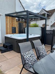 a hot tub on a patio with two chairs at Pen-Y-Worlod Cottages in Abergavenny