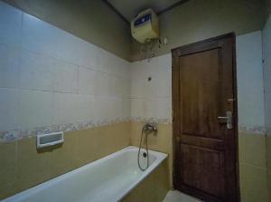 a bathroom with a bath tub and a wooden door at Hotel Indiana Syariah Mitra RedDoorz in Tanjung