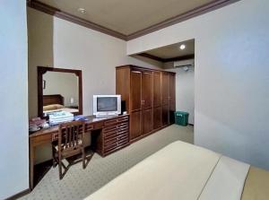 a bedroom with a desk with a tv and a mirror at Hotel Indiana Syariah Mitra RedDoorz in Tanjung