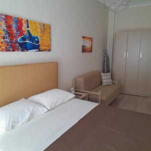 a bedroom with a bed and a couch and a painting at Zefi's Apartment in Nea Peramos