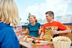 een groep mensen die rond een tafel zitten met eten bij Studio in der Alpine Lodge in Klösterle am Arlberg