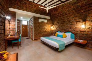 a bedroom with a bed and a brick wall at Lotus an Eco Beach Resort Dapoli Murud in Dapoli