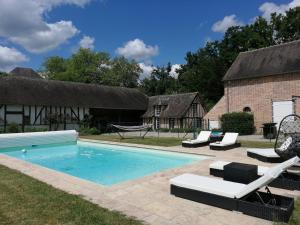 einen Pool mit Stühlen und einer Hängematte neben einem Haus in der Unterkunft Maison Blanche Sologne "La Framboisière" in Isdes
