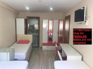 ein Zimmer mit zwei Betten und einem Fernseher an der Wand in der Unterkunft !ONLY FEMALES! Bakirkoy Ladies Dormitory in Istanbul