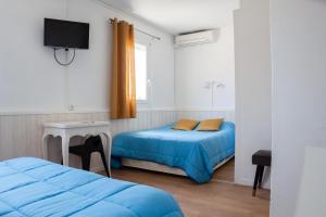 a room with two beds and a flat screen tv at Hotel La Casa in Le Barcarès