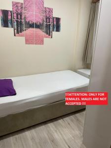 ein Bett in einem Zimmer mit rosa Gemälden an der Wand in der Unterkunft !ONLY FEMALES! Bakirkoy Ladies Dormitory in Istanbul
