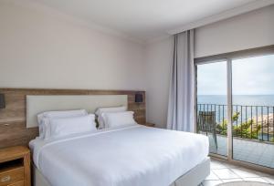 a bedroom with a large bed and a large window at Eden Roc Hotel & Spa by Brava Hoteles in Sant Feliu de Guíxols