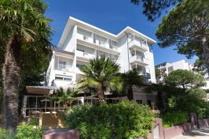 un edificio bianco con palme di fronte di Hotel Parco a Milano Marittima