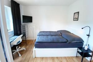a bedroom with a bed and a desk and a television at Business & Tourist Apartment with Balcony in Osnabrück