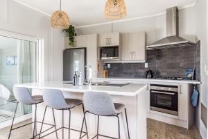 a kitchen with a white counter and stools at Left Break, Easy Family Escape in Raglan