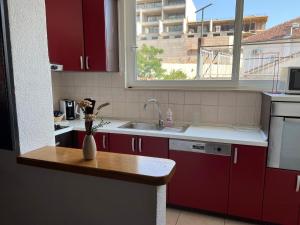 a kitchen with red cabinets and a sink and a window at Apartmani Kacola in Tučepi +12 photos