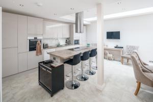 a kitchen with white cabinets and a island with bar stools at JOIVY Fabulous 4BR house with terrace at the heart of Notting Hill in London
