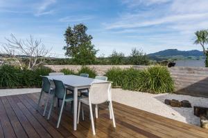 a white table and chairs on a wooden deck at Left Break, Easy Family Escape in Raglan