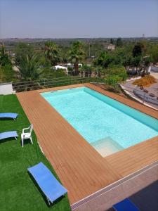 una gran piscina con una terraza de madera y sillas en Vivi Natura Agriturismo, en Gallipoli