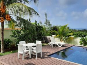 a patio with a table and chairs next to a pool at Emma's Guest House and Self-Catering in Au Cap