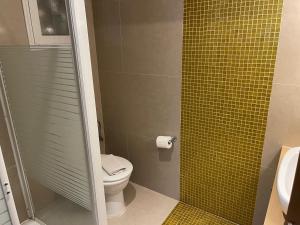 a bathroom with a toilet and a yellow tile wall at Plaza Hotel in Hanioti