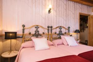 a bedroom with a pink bed with white pillows at Casa rural el gato encantado in Matalebreras