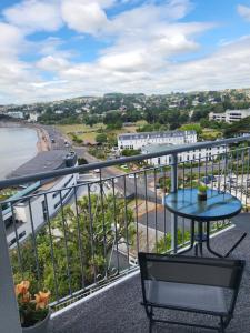 uma varanda com uma mesa e vista para a praia em Loveliest Homes Torquay - 3 bed, 2 bathroom, balcony, parking em Torquay