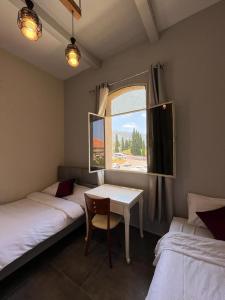 a room with two beds and a table and a window at Diamond Apartment In Haifa in Haifa