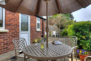a table and chairs with an umbrella on a patio at 23 Lym Close in Lyme Regis