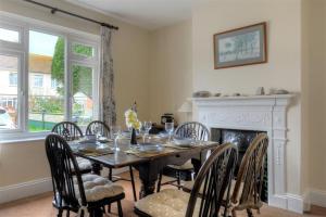 a dining room with a table and chairs and a fireplace at 23 Lym Close in Lyme Regis +10 photos
