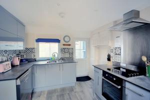 a large kitchen with white cabinets and a sink at 1 Cobb View in Lyme Regis