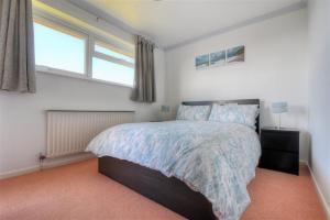 a bedroom with a large bed and two windows at 38 Wessex Court in Lyme Regis