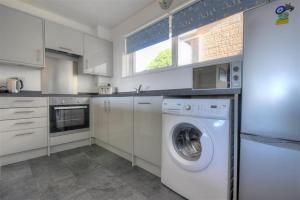 a white kitchen with a washing machine in it at 38 Wessex Court in Lyme Regis