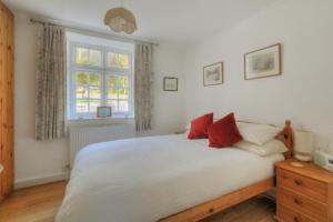 una camera da letto con un grande letto bianco con cuscini rossi di Windwhistle a Lyme Regis