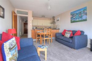 a living room with two blue couches and a kitchen at 4 Bay View Court in Lyme Regis +7 photos
