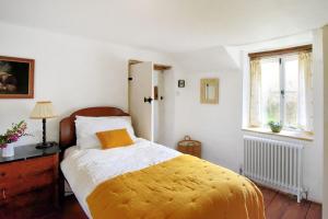 a bedroom with a bed with a yellow blanket on it at Church Cottage in Whitchurch Canonicorum