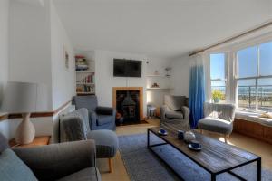 een woonkamer met een bank en stoelen en een open haard bij Captains House in Lyme Regis