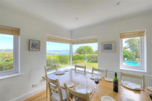 a dining room with a table and chairs and windows at Somerhill in Lyme Regis