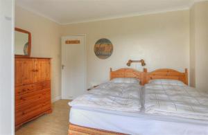 una camera con letto in legno e cassettiera di West Ridge Bungalow a Seaton