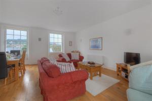 Una sala de estar con dos sillas rojas y una mesa. en Rooftops, en Lyme Regis