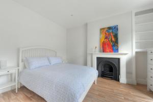 a white bedroom with a bed and a fireplace at 3 Major Terrace in Seaton