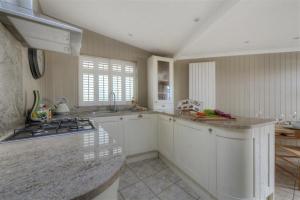 uma cozinha com armários brancos e uma bancada em The Lodge em Lyme Regis
