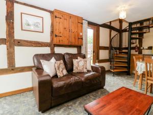 sala de estar con sofá de cuero marrón y mesa en Holly Bush en Pembridge