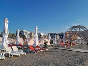 eine Gruppe von Liegestühlen und Sonnenschirmen an einem Strand in der Unterkunft Morsky in Năvodari