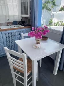 Una mesa blanca con un jarrón de flores. en Ονειρόπετρα Λέρος~Oneiropetra Leros, en Panteli