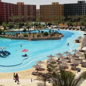 a large pool with umbrellas and people on the beach at تمتع بالإقامة في شاليه فندقي بمنتجع جولف بورتو مارينا الساحل الشمالي - Enjoy your stay at Golf Porto Marina Resort El Alamein - North Cost in El Alamein