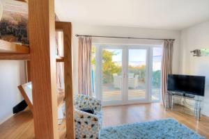 a living room with a television and a sliding glass door at Little Bay View in Lyme Regis