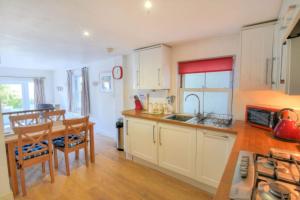 a kitchen with white cabinets and a table and a dining room at Little Bay View in Lyme Regis